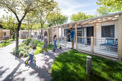 a family playing with scooters outside of a house at Camping Village Garden Paradiso in Cavallino-Treporti