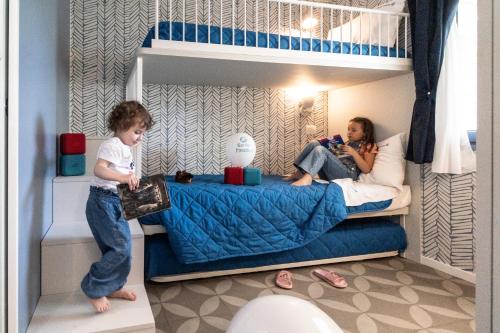 a young child standing in a bunk bed with a woman at Camping Village Garden Paradiso in Cavallino-Treporti
