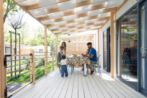 a family sitting at a table on the deck of a house at Camping Village Garden Paradiso in Cavallino-Treporti