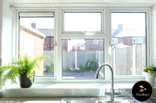 a kitchen sink with a window above a kitchen counter at Bee Stays - Ambleside House in Warrington