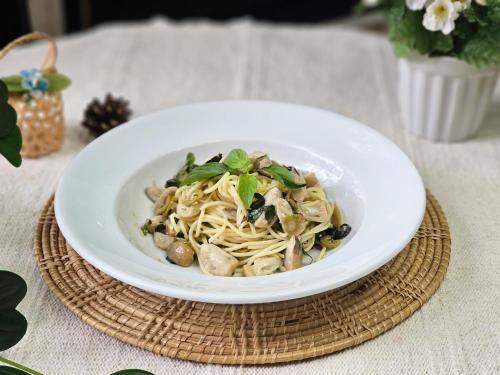 a white bowl of noodles and mushrooms on a table at Cosy Beach Hotel - SHA Extra Plus in Pattaya South