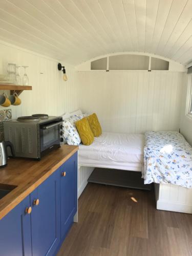 um pequeno quarto com uma cama e um micro-ondas em Shepherds Hut with Hot Tub em Wells