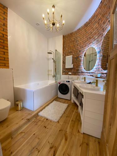a bathroom with a tub and a sink and a mirror at Apartments PSD - Anny Łajming 2C in Słupsk