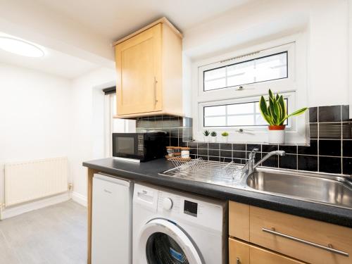 a kitchen with a sink and a washing machine at Pass the Keys King s Cross Urban Oasis in London
