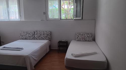 a room with two beds and two windows at El Colmenar Habitaciones in Madrid