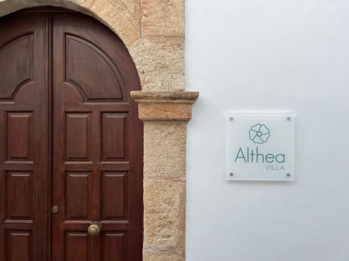 drewniane drzwi i znak obok budynku w obiekcie Althea Villa w Líndos