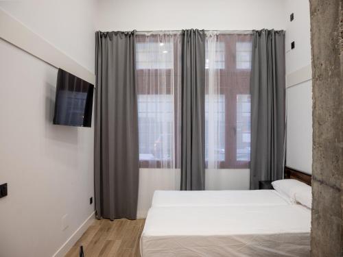 um quarto com uma cama e uma janela em VR OBREGON APARTMENTS em Madrid