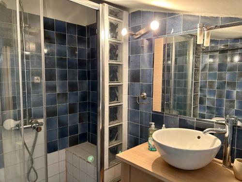 uma casa de banho em azulejos azuis com um lavatório e um chuveiro em Studio avec piscine em La Garde-Freinet