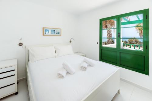 - une chambre avec un lit blanc et une porte verte dans l'établissement Lanzahost Tuscan Atlantico, à Costa Teguise