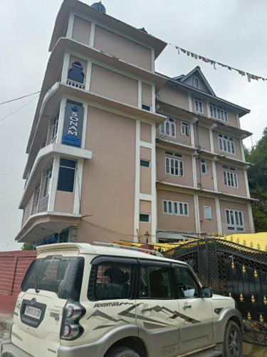 a white suv parked in front of a building at Vamoose Sonam Guest House Tawang in Tawang