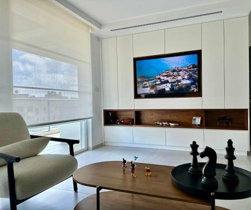 a living room with a table and a tv at Suite In White in ‘Akko