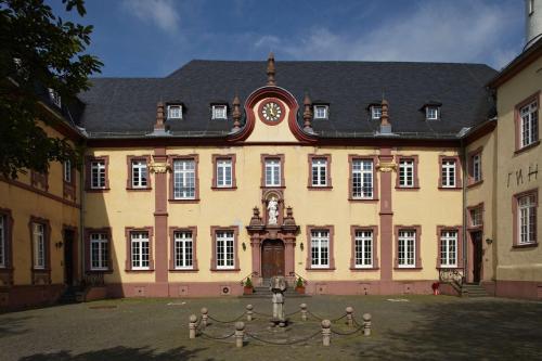 Kloster Steinfeld Gästehaus في Kall: مبنى كبير يوجد امامه ساعه