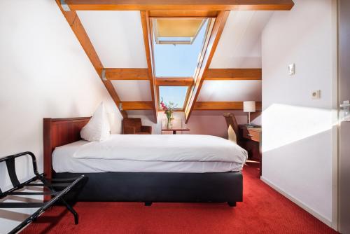 a bedroom with a large bed with a window at Hotel De Schildkamp in Asperen
