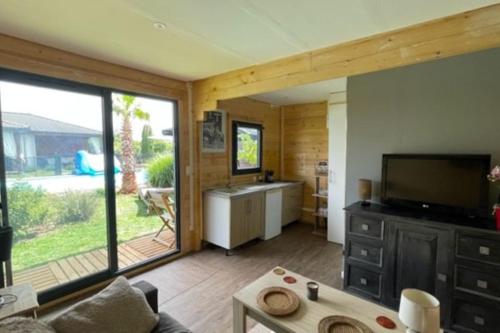 sala de estar con ventana grande y TV en Chalet cosy avec piscine chauffée, en Beauregard-lʼÉvêque