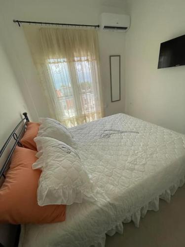 1 cama blanca en un dormitorio con ventana en Διαμέρισμα στη Ναύπακτο, en Nafpaktos