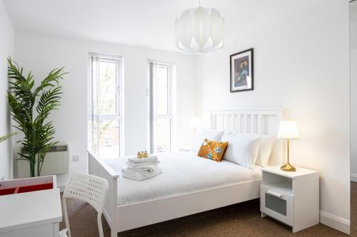 a white bedroom with a white bed and a lamp at The Chorlton in Manchester