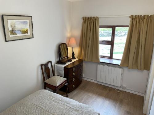 a bedroom with a bed and a dresser and a window at Flaherty Cottage, Ballyconneely in Ballyconneely