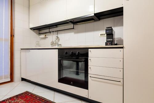 een keuken met een zwarte oven en witte kasten bij i cedri in Turijn