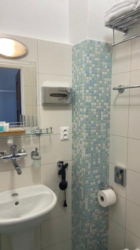 a bathroom with a sink and a shower with a mirror at Aparthotel Slezák in Litomyšl