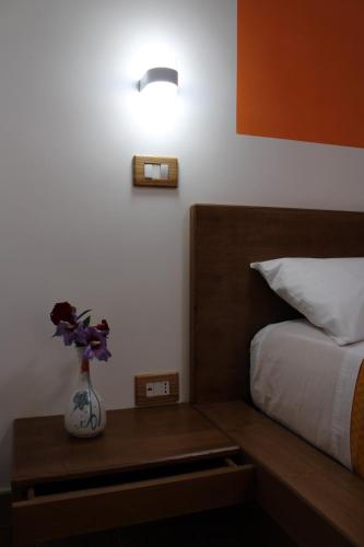 1 dormitorio con 1 cama y un jarrón de flores sobre una mesa en Zia Bianca BeB, en Vietri