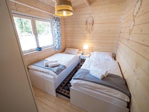 two twin beds in a room with wooden walls at Kolorowe Zacisze 
