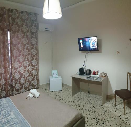 1 dormitorio con escritorio y TV en la pared en Stella Maris, en Palermo