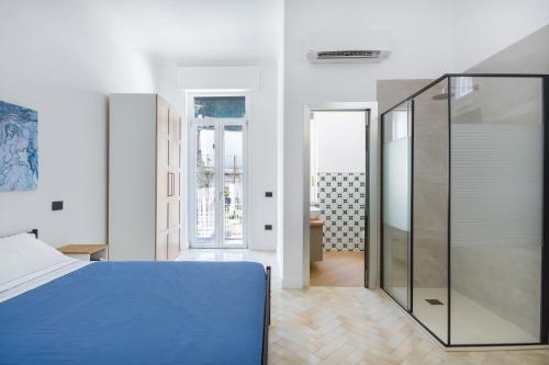1 dormitorio con cama azul y ducha a ras de suelo en Ammos Suite Sorrento Coast, en Castellammare di Stabia