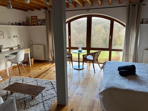 uma sala de estar com uma cama e uma mesa e um quarto com uma mesa em Les deux chambres au dessus de la colline em Namur