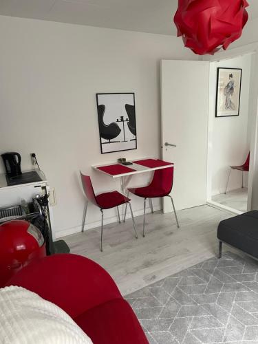 a bedroom with red chairs and a white table at Løkke-bo in Løkken
