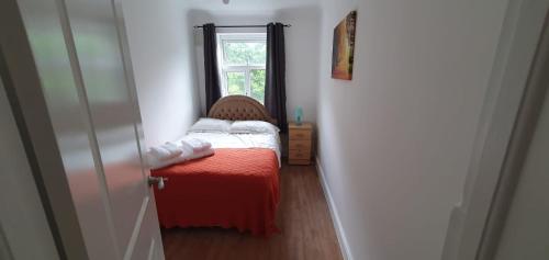 a small bedroom with a bed and a window at Lovely 3 Bedrooms Flat Near Romford Station With Free Parking in Romford