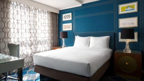 a bedroom with a large bed and a blue wall at The Ven at Embassy Row, Washington, D.C., a Tribute Portfolio Hotel in Washington