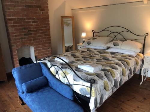 a bedroom with a large bed and a blue couch at Cherry Tree Cottage Close to Belvoir Castle. Sleeps 6. Dogs v welcome. in Redmile