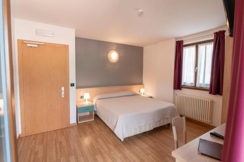 1 dormitorio con cama, ventana y puerta en Hotel Posta en Comano Terme