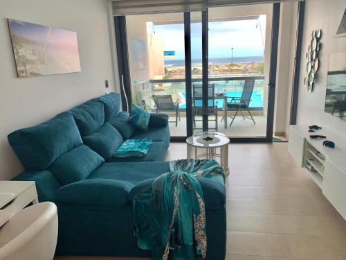 a living room with a blue couch and a balcony at Calypso in Cotillo