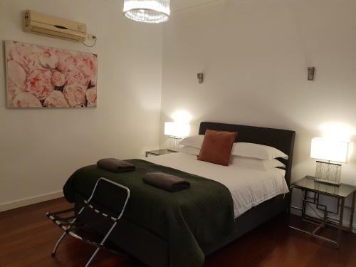 フリーマントルにあるLeisurely Manor - spacious three bedroom home in Fremantleのベッドルーム1室(ベッド1台、テーブル2台、ランプ2つ付)