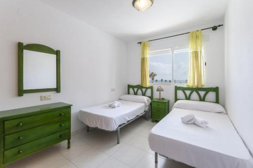 1 dormitorio con 2 camas, espejo y ventana en Begonia, en Daimuz