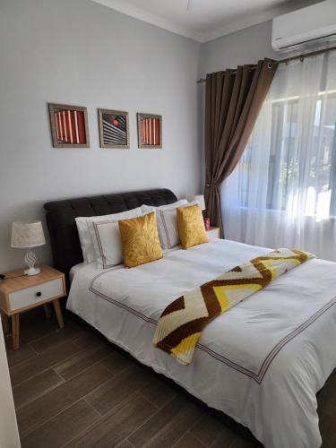 a bedroom with a large bed and a window at SaronaC102 in Gaborone