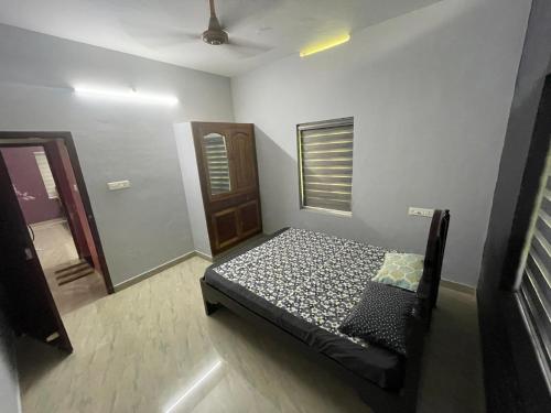 a bedroom with a bed in the corner of a room at Nisara Homestay in Varkala