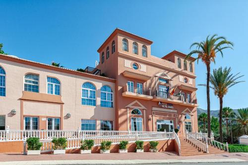 a large building with palm trees in front of it at Bahía Tropical in Almuñécar