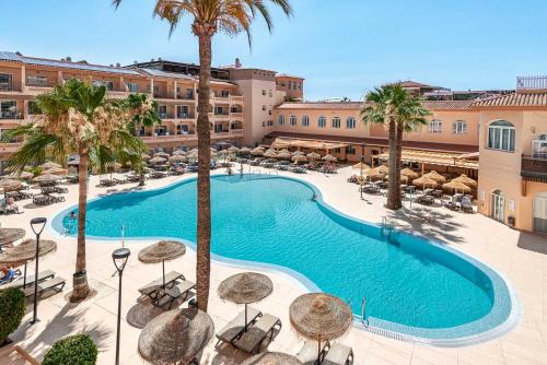 an overhead view of a swimming pool with palm trees and umbrellas at Bahía Tropical in Almuñécar