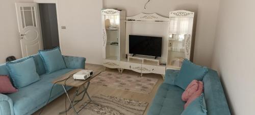a living room with two blue couches and a television at TERMAL LUX HOUSE in Yalova