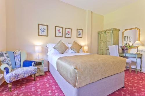 een hotelkamer met een bed en een stoel bij Burn How Garden House Hotel in Bowness-on-Windermere