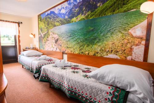 two beds in a hotel room with a painting on the wall at Willa Kubik in Zakopane