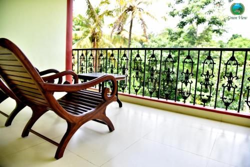 a wooden bench sitting on a balcony with a view at Green View in Thekkady