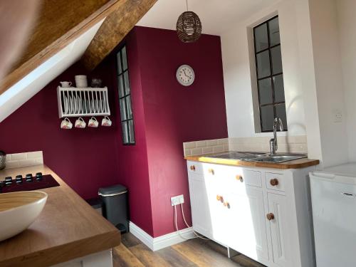 Studio Apartment في ويلْزْ: مطبخ مع دواليب بيضاء وجدار احمر