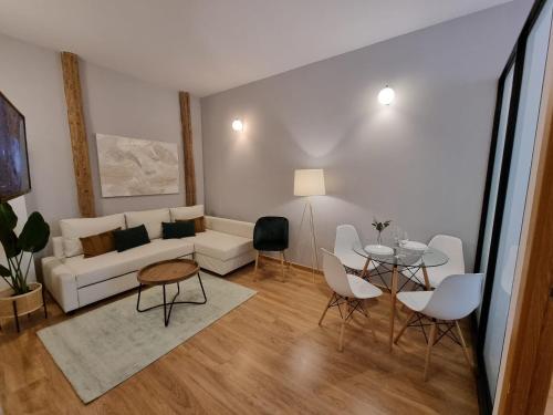 sala de estar con sofá, mesa y sillas en Apartamentos San Isidro, en Madrid