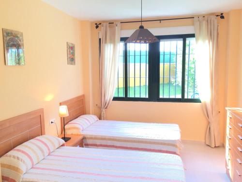 two beds in a room with a window at APARTAMENTO DE 2 DORMITORIOS APARTACLUB in Chiclana de la Frontera