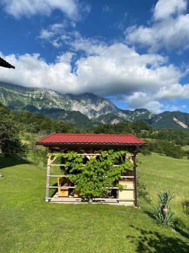 a gazebo with a red roof in a field at Apartma Logar in Kobarid