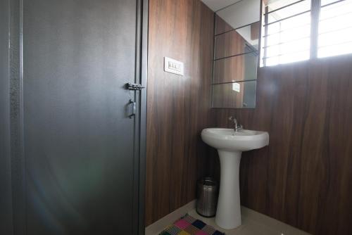baño con lavabo, espejo y puerta en Kanasu StayHome, en Chikmagalur