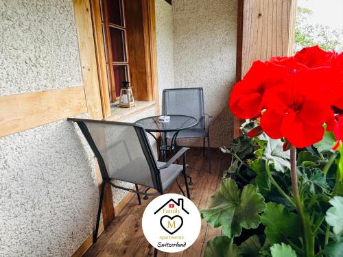 a patio with two chairs and a table and red flowers at Family M Apartments 15 in Kappel bei Olten